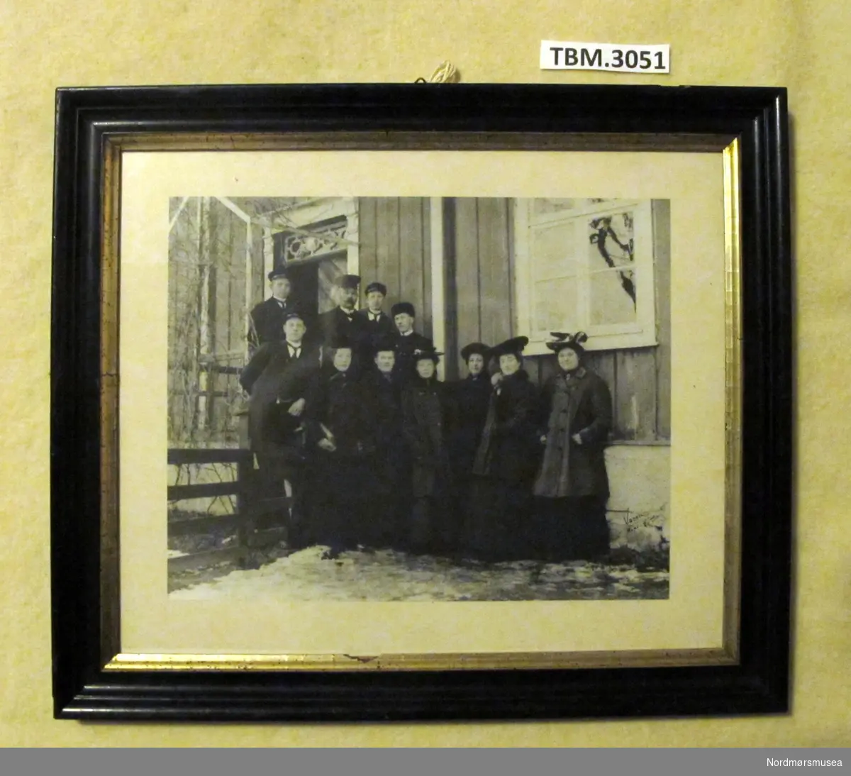 Bildet viser 11 personar på trappa utafor Bugges Minne.
Framhaldskoleklasse frå 1908.
Ramma er svart med gullkant inst.