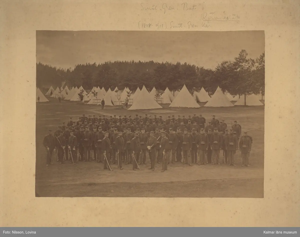 KLM 18175. Fotografi, på kartong. Militär bild. Gruppfotografi av Kalmar regemente på Hultsfred slätt, fältgata med tält.