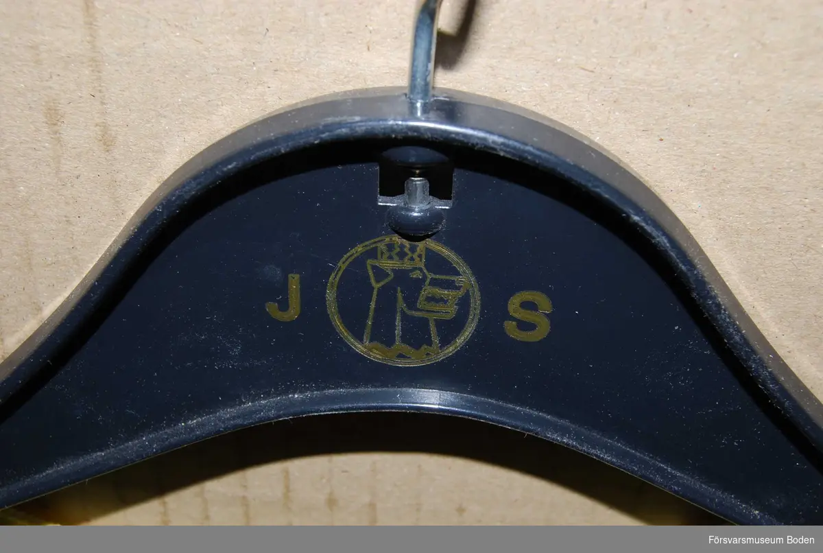 Gul med svart text. Galgen har påtrycket "J S" och Jägarskolans vapen.