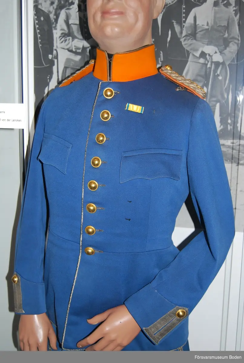 Mellanblå med regementets orangegula färg på kragen och på axelklaffarnas mattor. Enkel rad med knappar av regementets modell.