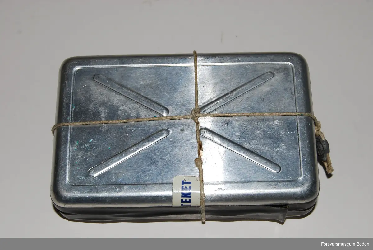 Plomberad aluminiumdosa 7,5 x 12 cm. Bör innehålla förbandspaket för bränn- och sårskador. Materielnummer M8280-365010.