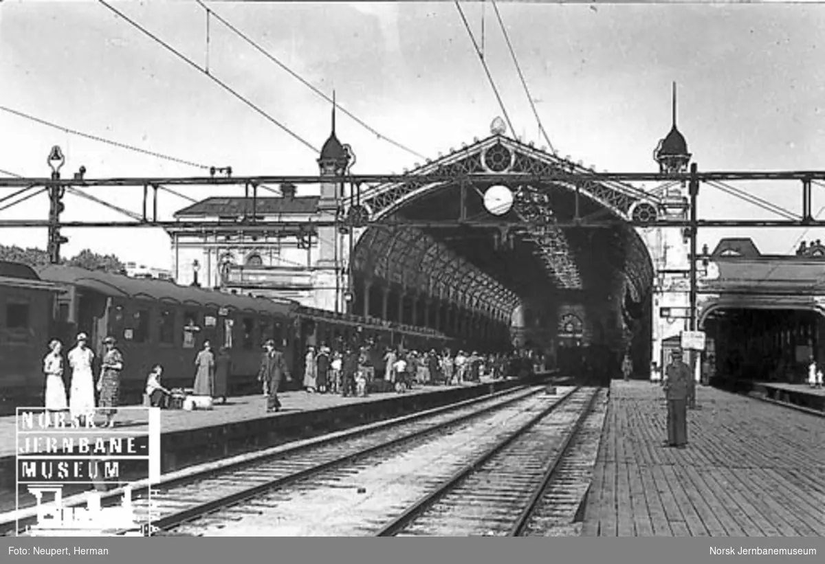 Reisende på plattformen Østbanen med toghallen i bakgrunnen