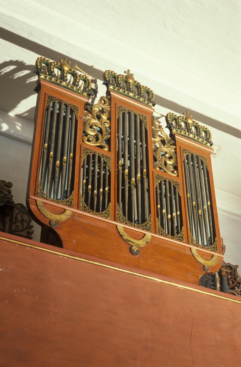 Figurer som troner øverst på orgelet: David som spiller på harpe og to engler som spiller basun. 