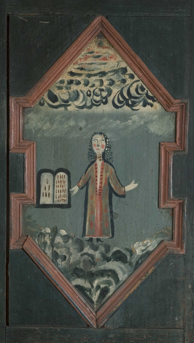 Skap, framskap i en del, to dører oppe og nede. Bibelske motiver; Moses og de ti bud. Gud på en sky, en brennede sky eller busk, en mann som har mistet en sko og en stokk.