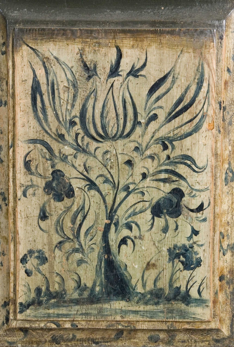 Framskap i to deler. Buet topplist. Skuffer og skjehylle i overskap. Malt innvendig og utvendig. Kirke og bygning malt på dør på overskap. Planter på underdel. Marmorert på lister på overskap.