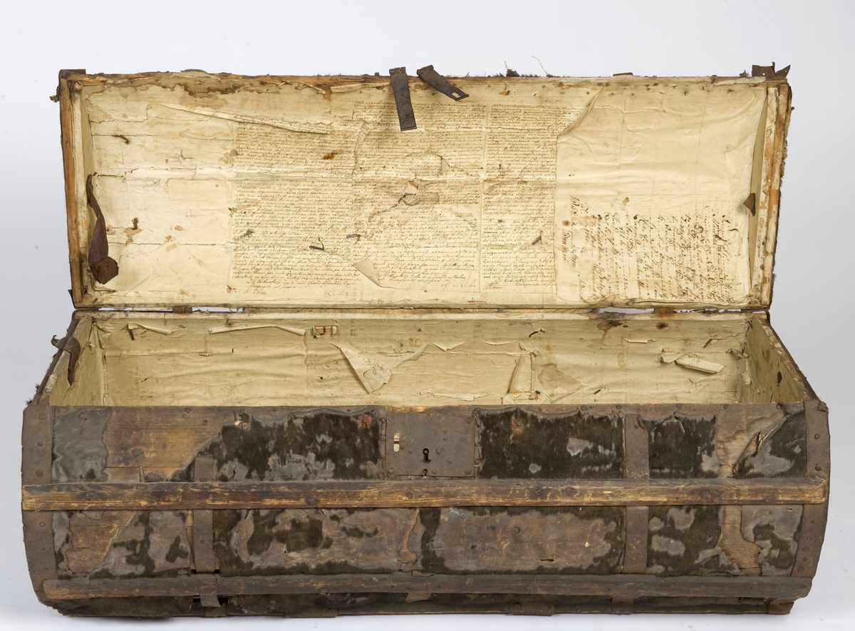 Rund kiste trukket med selskinn og med jernbeslag. Innsiden foret med håndskrevne brev på papir hvorav to er datert 1780.