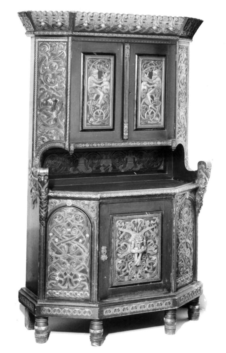 Skåret av treskjæreren Lars Kinsarvik (1846-1925), som utviklet sin særegne variant av drakestilen. Kinsarvik drev egen treskjærerskole, og var fra slutten av 1880-årene lærer ved Kristiania Kunstindustrimuseum.