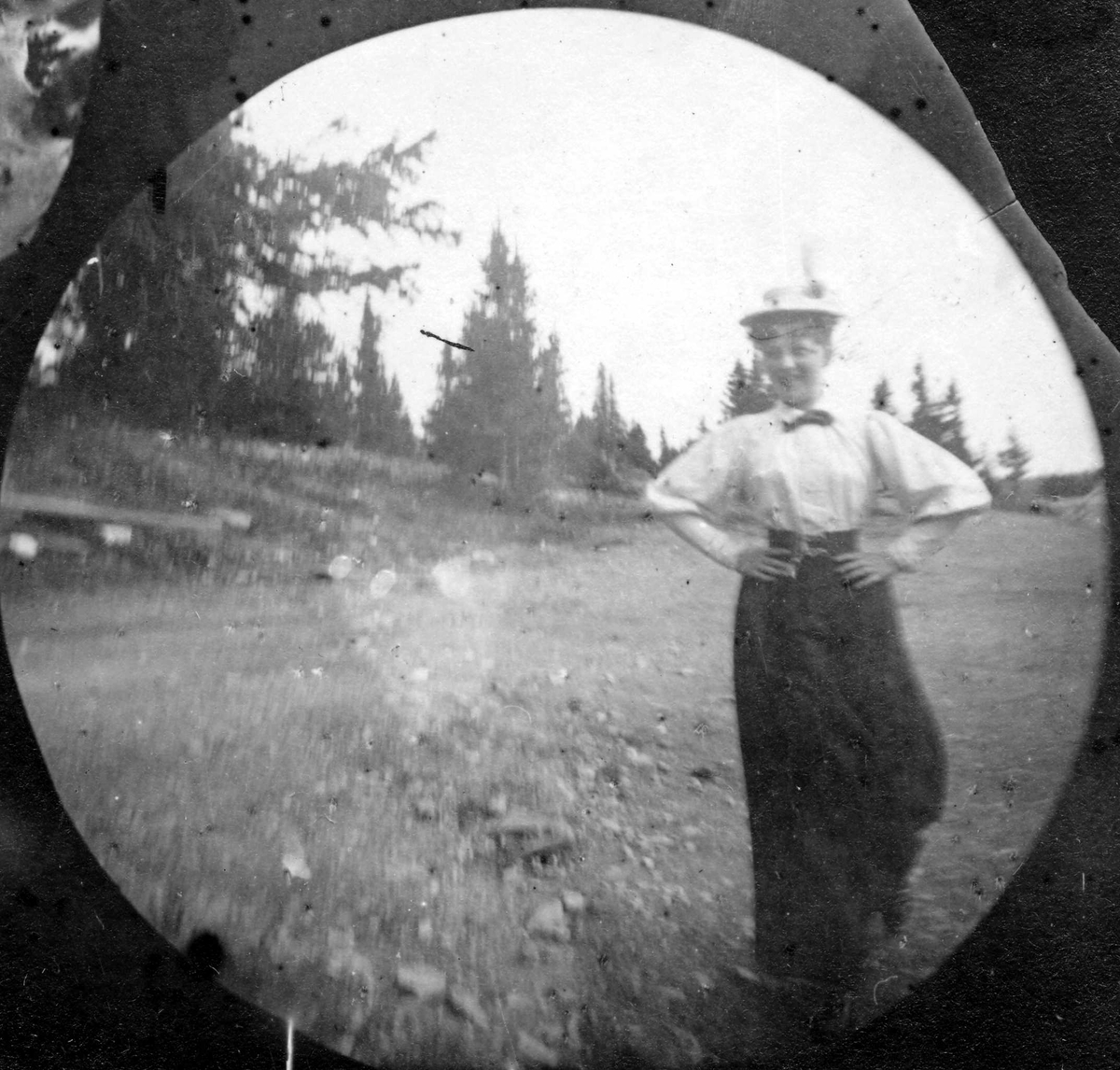 Frk. Anna Holm med mørkt skjørt, hvit bluse og hatt i skogen, Golå, Sør-Fron, Oppland.