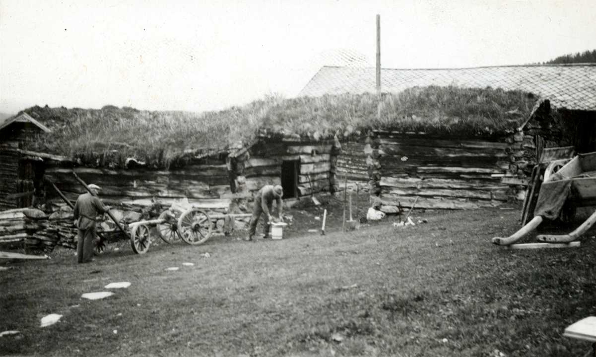 Engan, Os, Nord Østerdal, Hedmark 1941. Fjøs og løe i tømmer med torv på taket. To menn arbeider på gårdsplassen. Hestekjøretøy. Nå på Norsk Folkemuseum.
