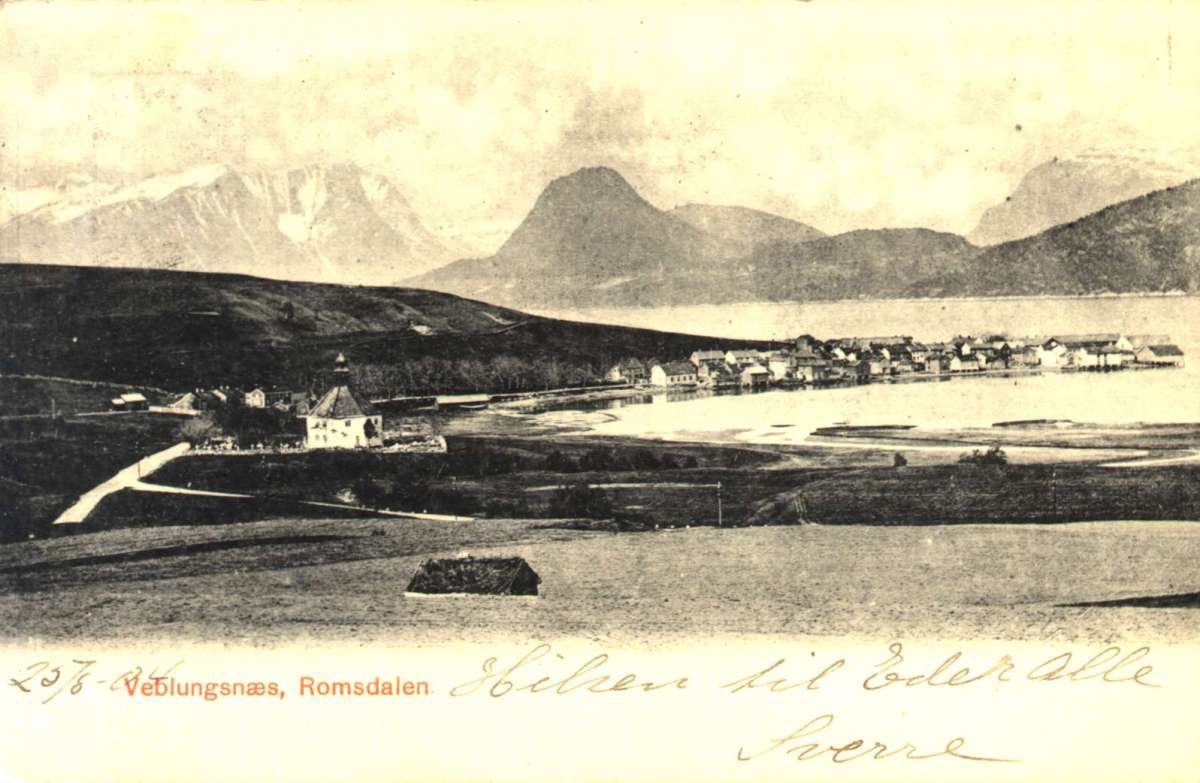 Postkort. Grytten kirke sees i forgrunn, hus ligger langs sjøen med fjell i bakgrunn, Veblungsnes, Rauma. Stemplet 28.08.1904.