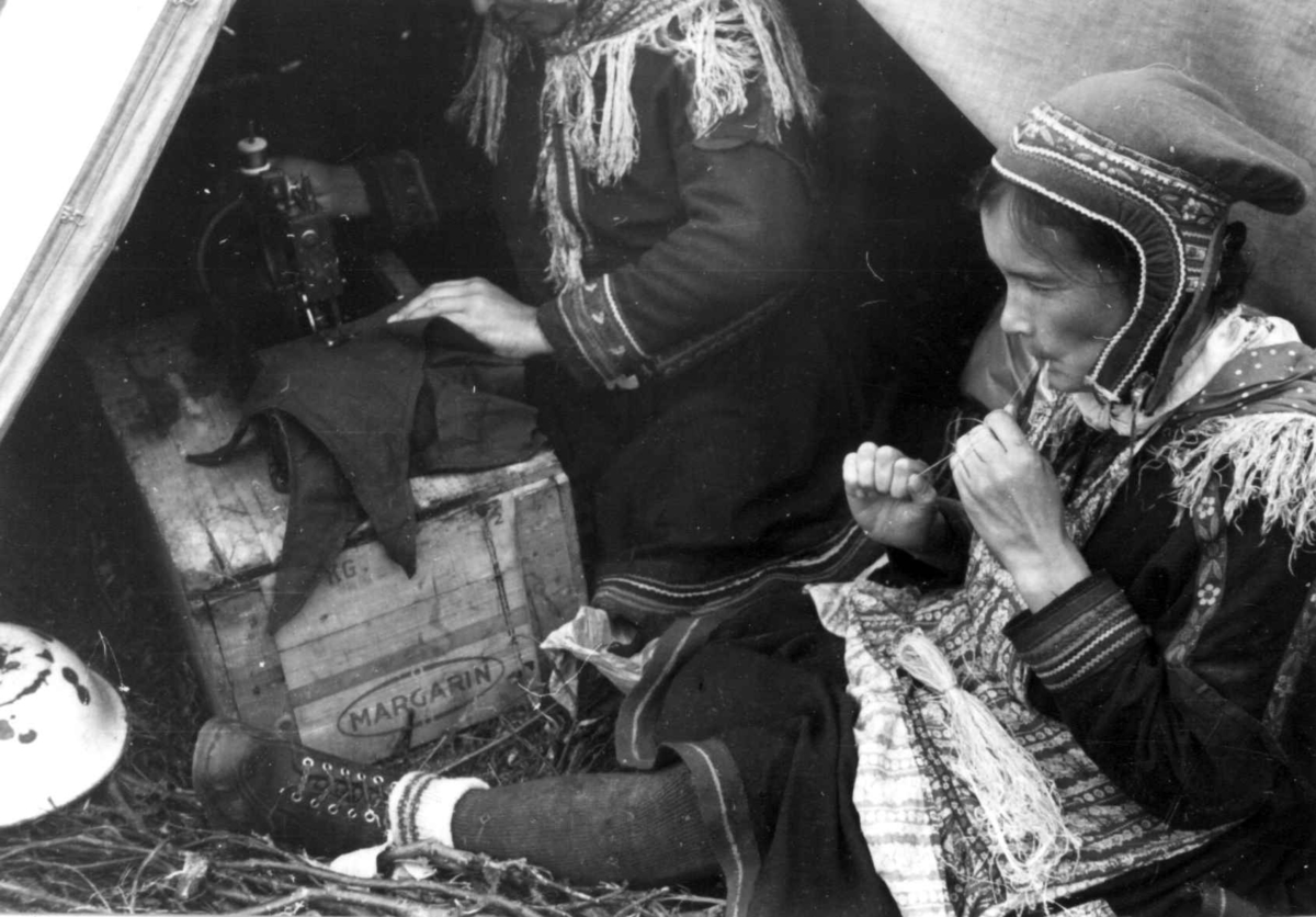 En kvinne bearbeider senetråd og en annen kvinne syr på symaskin. Olderdalen, Kåfjord, Troms 1947.