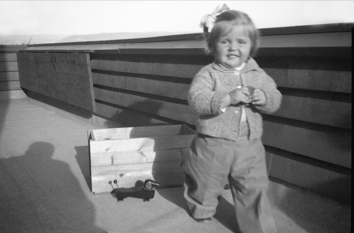Kari Arentz på veranda med leker rundt seg. Fotografert 1936.