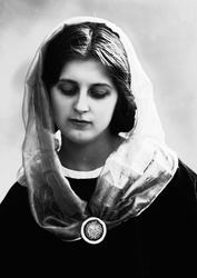 Studioportrett av kvinne i drakt og sjal, med brosje i halse