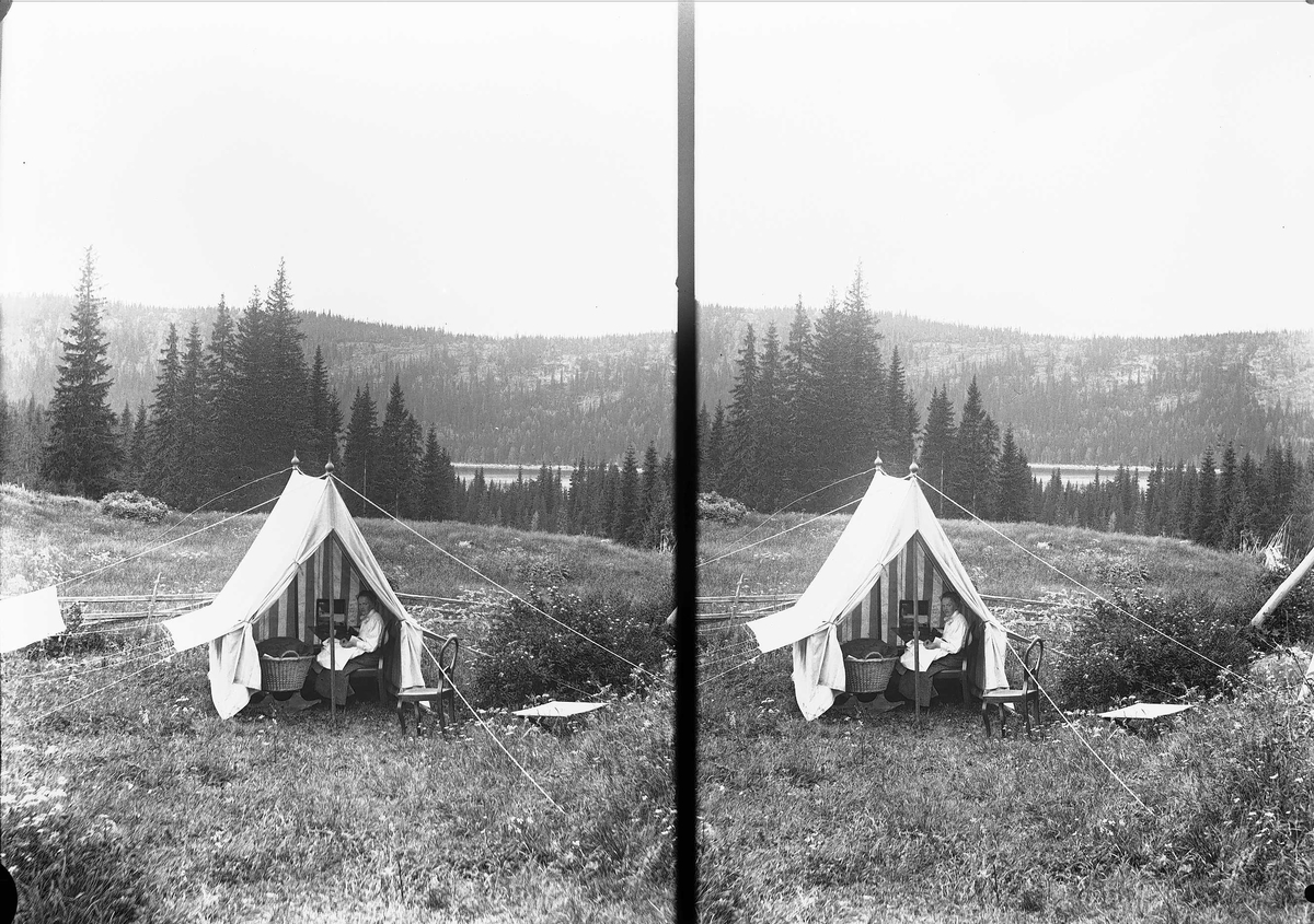 Margrethe Q. Wiborg sitter i telt med kurv ved Holoa seter, Hadeland, Jevnaker, Oppland, 1903. Utsikt til Skarvvannet.