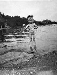 En jente står å poserer i vannet. Robsahm og Lund.