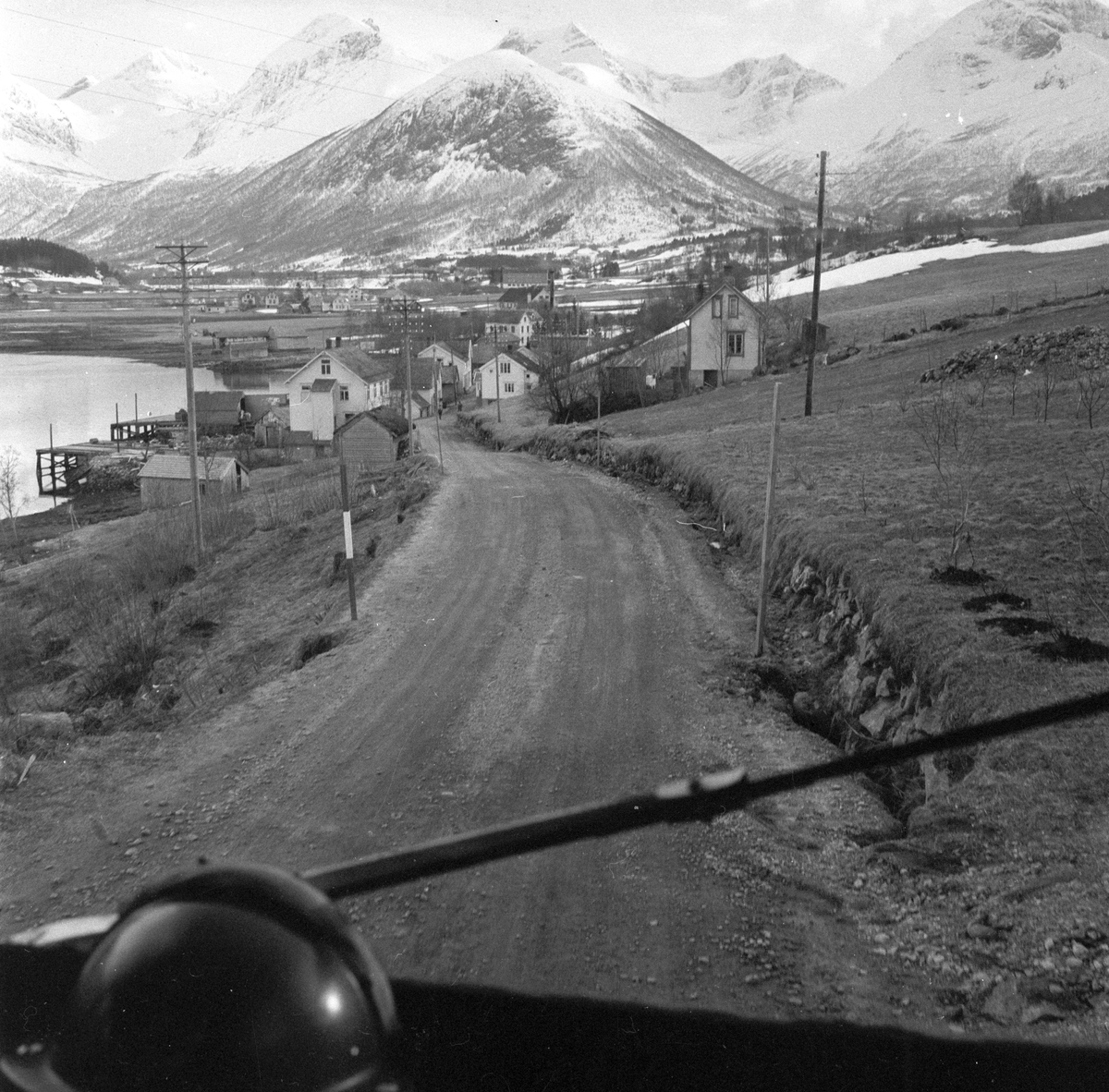 "NSB Bilruter" på veien mellom Ålesund og Åndalsnes. På vei inn mot tettsted. Fotografert 14. april 1956.