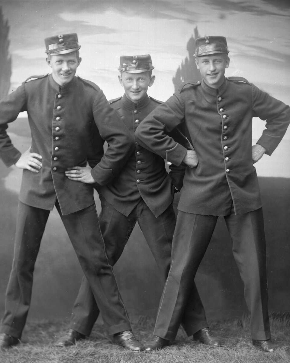 Gruppe, tre soldater i uniform med hender i sidene eller lommene. Umilitær positur.