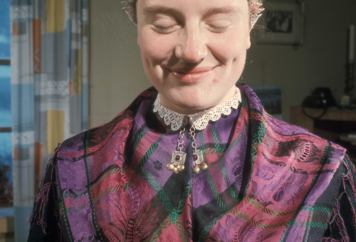 Brudepynting, Jølster 1967.Bruden, Eva Eide, får hjelp av Maria Gjesdal  med påkledningen.
Halskragen med halsknappen og berakluten.