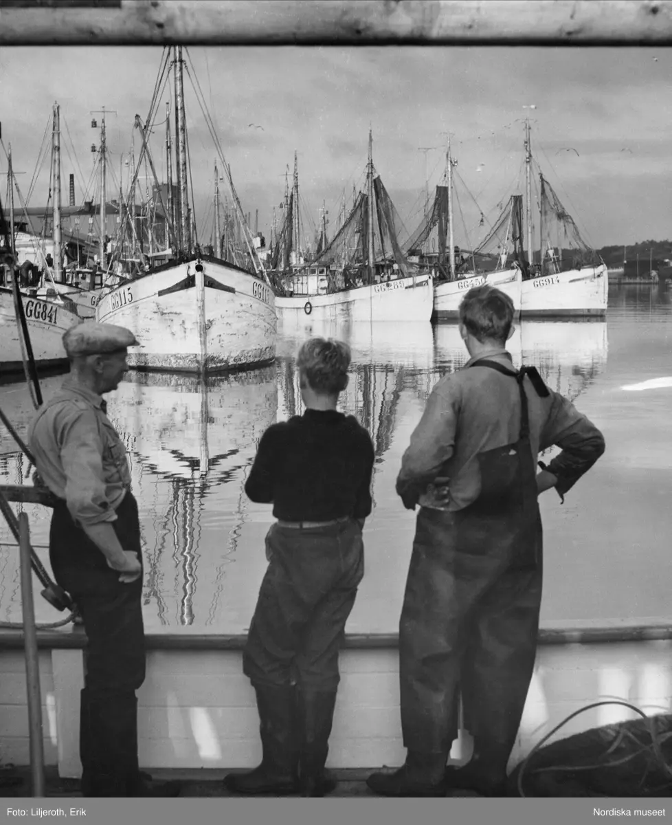 Göteborg. Tre fiskare som tittar ut över hamnen och fiskebåtarna