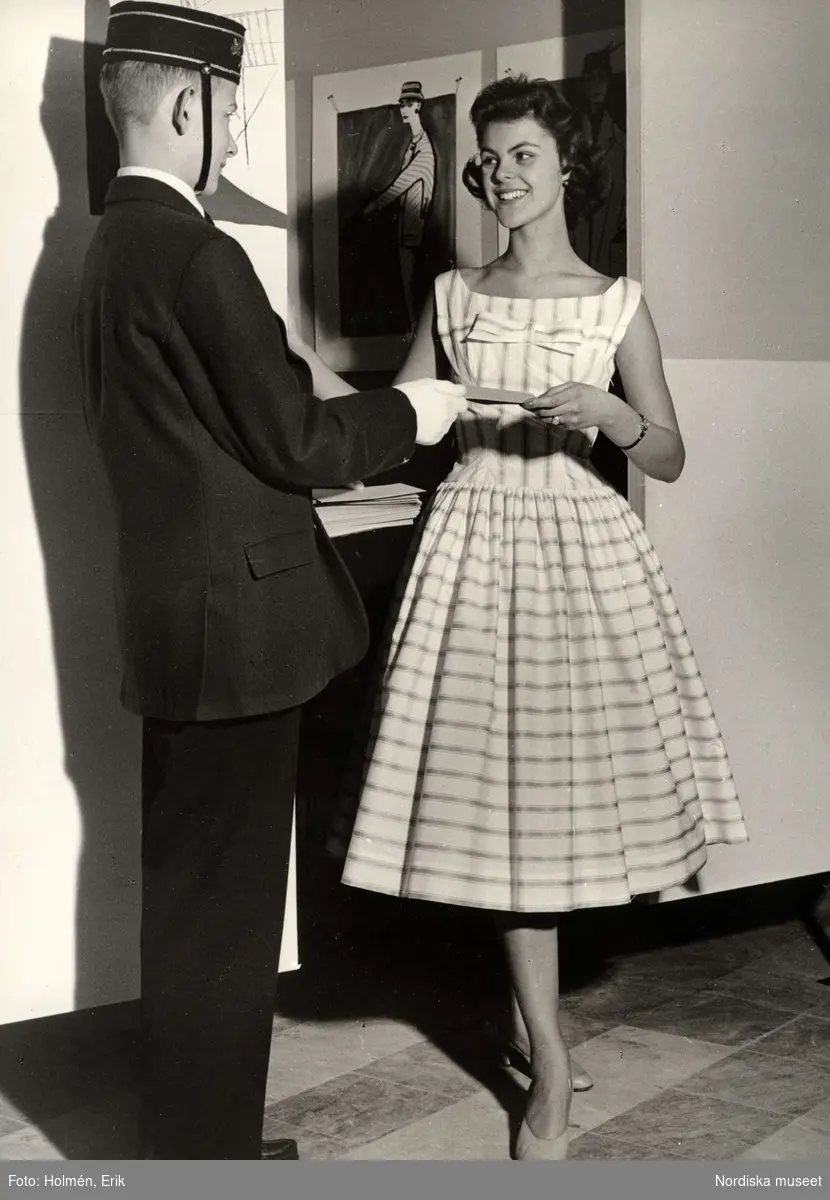 Piccolo räcker ung kvinna ett brev. Tonårsmode, Nordiska Kompaniet 1956.