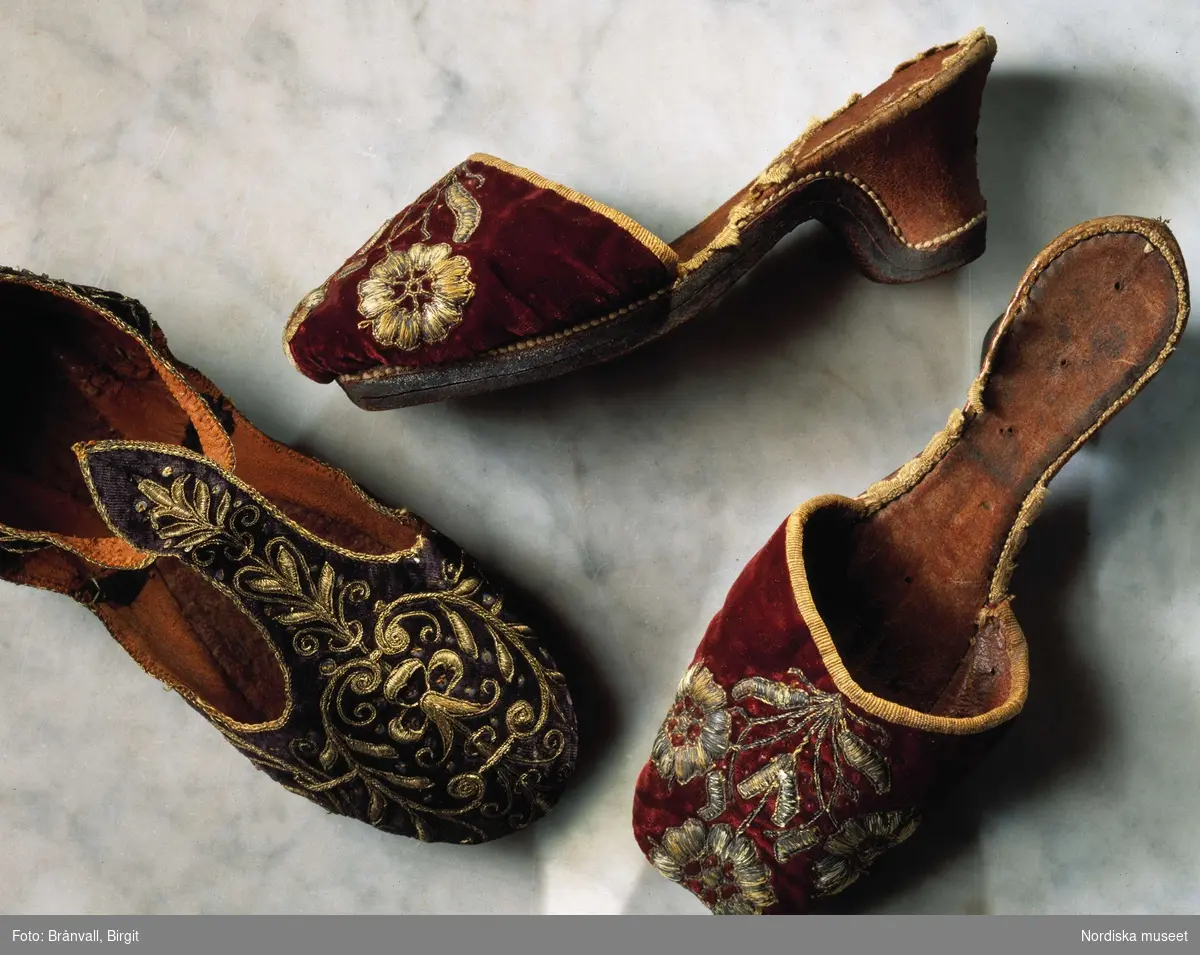 Praktfulla damtofflor av röd sammet, broderade med guldtråd och fodrade med brunt skinn. Första hälften av 1600-talet. Ur Nordiska museets samlingar.