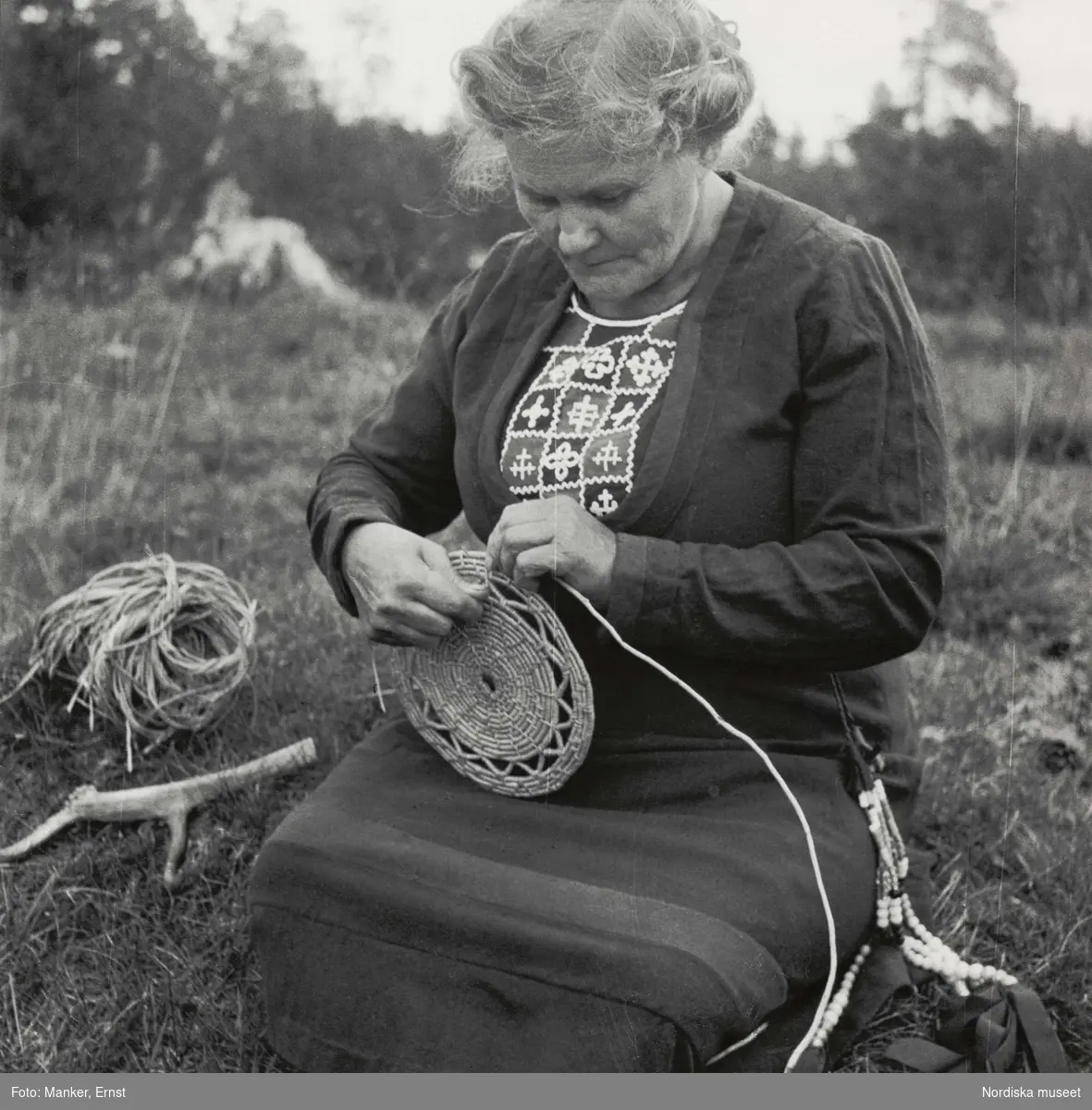 Korgflätning. Maria Larsson (f. Nilsson), dotter till den berömda korgfläterskan Stor-Stina i Glen, flätar en korg.
Mittådalens lappby, Härjedalen, Storvallen. L.A. 820