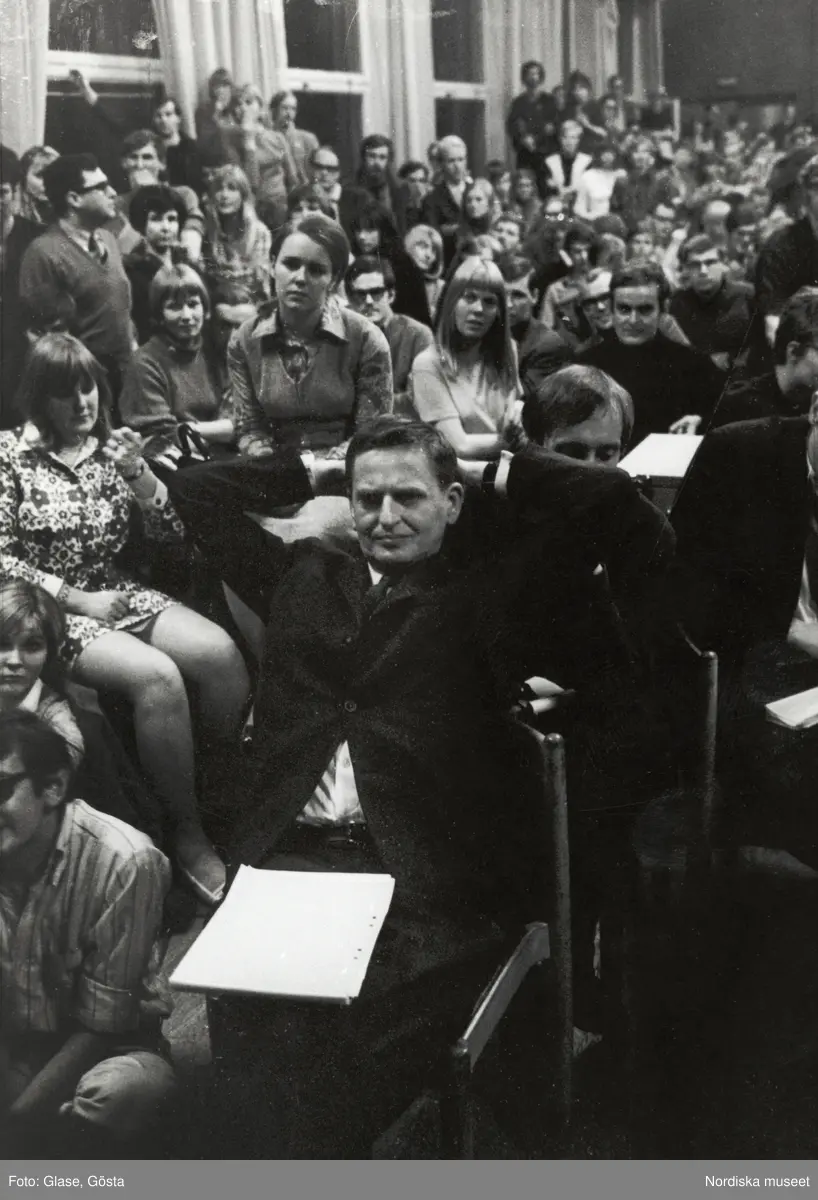 Kårhusockupationen vid Stockholms universitet i slutet av maj 1968. Bland åhörarna, i en stol, med händerna knäppta i nacken, sitter dåvarande utbildningsminister Olof Palme. 