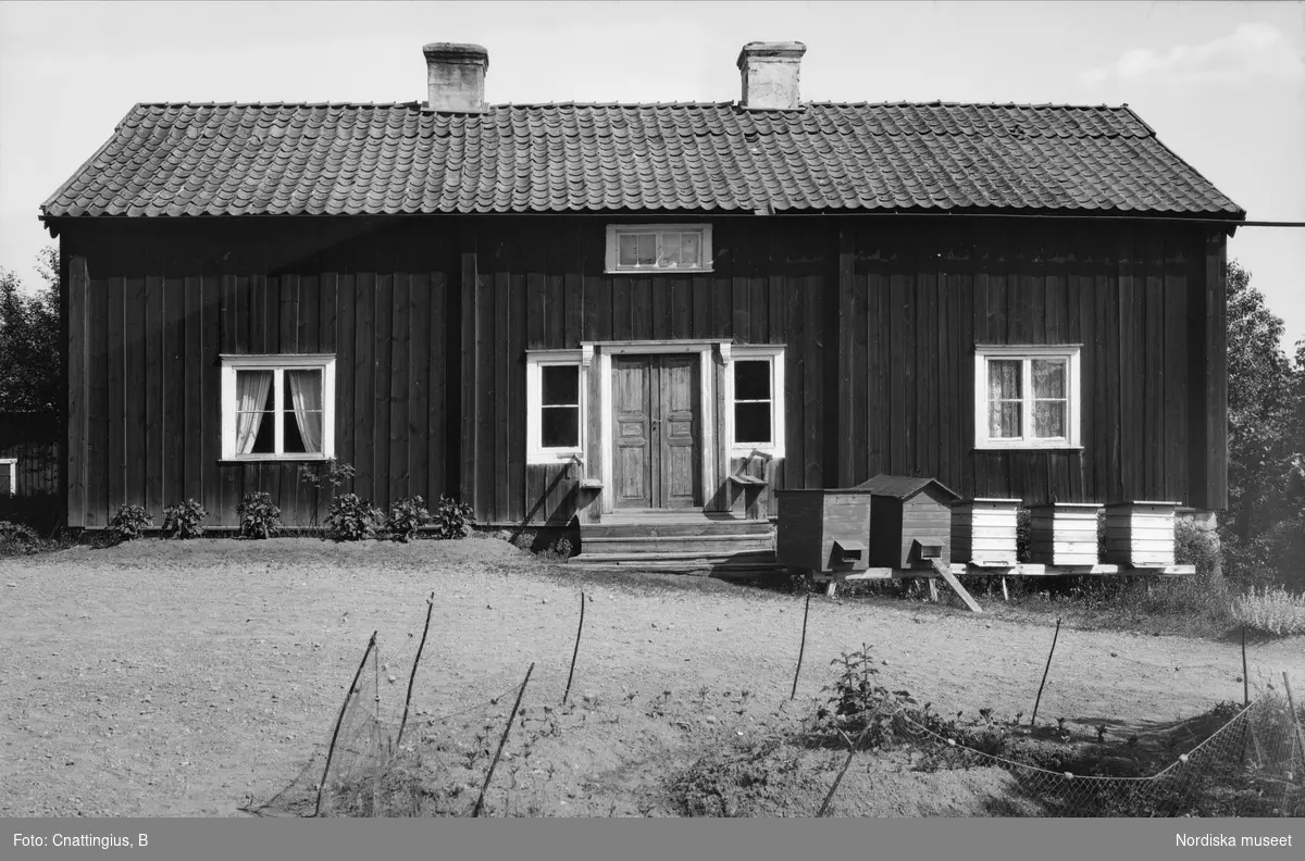 Gamla komministergården sedd från sydost. Djursdala socken, Sevede härad, Kalmar län, Småland. Låg träbyggnad med stående panel och dubbeldörrar.