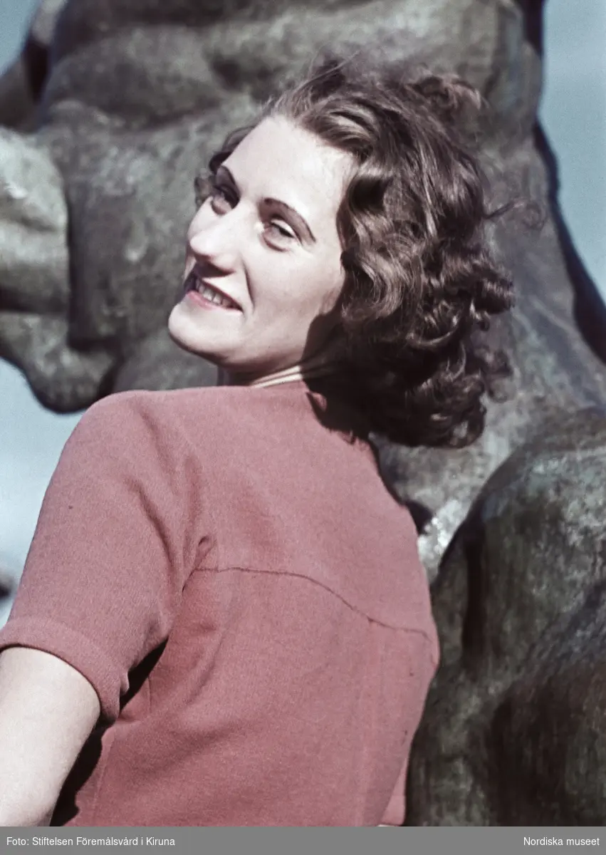 Kvinna iklädd röd blus. I bakgrunden Sigrid Frimans skulptur Kentauren från 1939 i Observatorielunden.