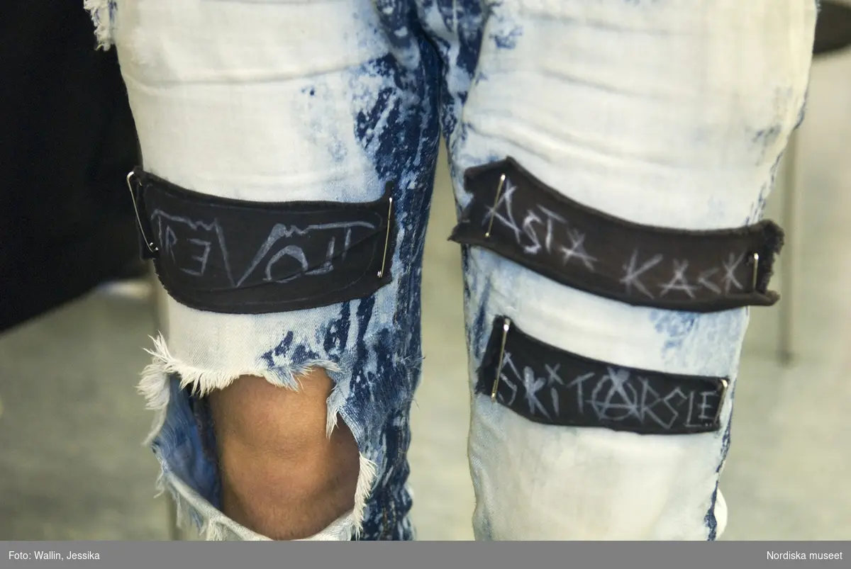 Dokumentation av ungdomsmode i Täby enskilda gymnasium hösten 2009. Trasiga jeans med lappar med text fästade med säkerhetsnålar.