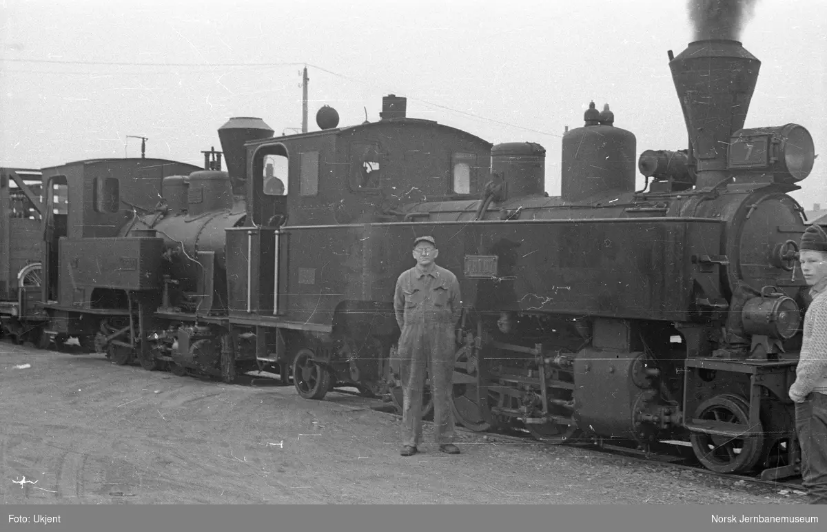 Damplokomotivene "Prydz" og "Urskog" i tog med UHBs verksmester Julius Engen foran det fremste lokomotivet. Bildet er tatt i forbindelse med transport av materiell fra UHB til Jernbanemuseet.