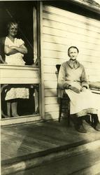 Eldre kvinne sittende ved ved inngangsdør. En kvinne står in