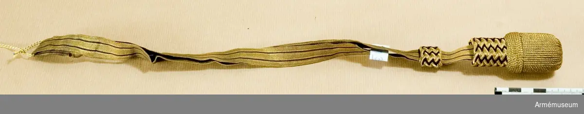 Sabelhandrem av guldgalon och svart silke med stel tofs i gulddrageriarbete. Längd: 470 mm. Bredd: 18 mm.
Använd vid Göta/Wendes artilleriregemente.