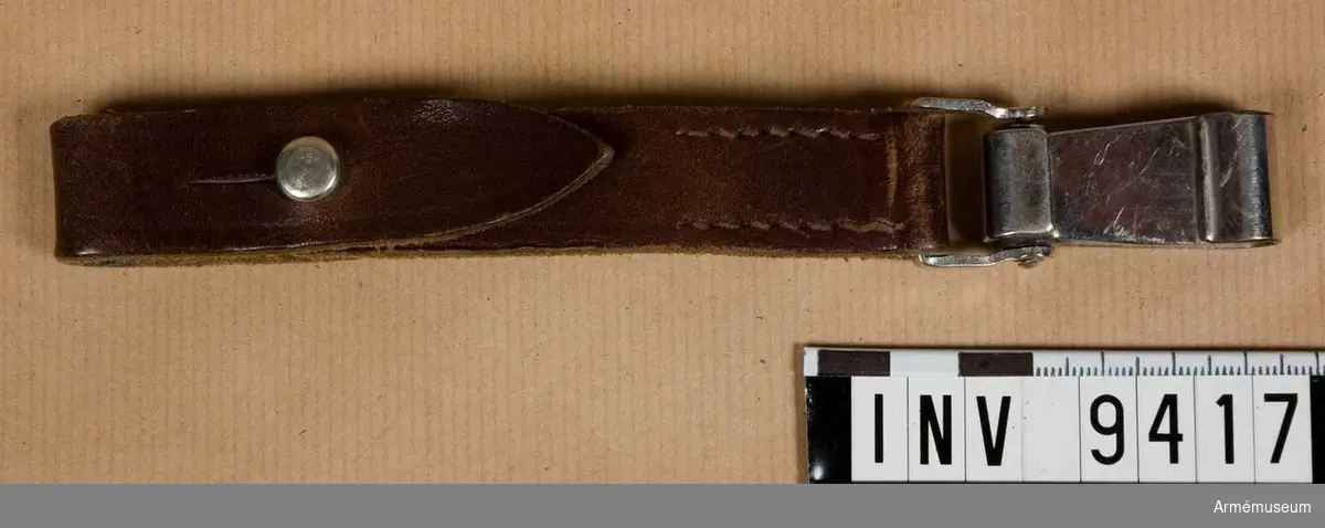 Samhörande nr är 9411-9422.
Den är gjord i läder med en karbinhake i vitmetall. På den övre läderdelen finns en övervikt läderdel i vilken sabelkopplet är fäst.
