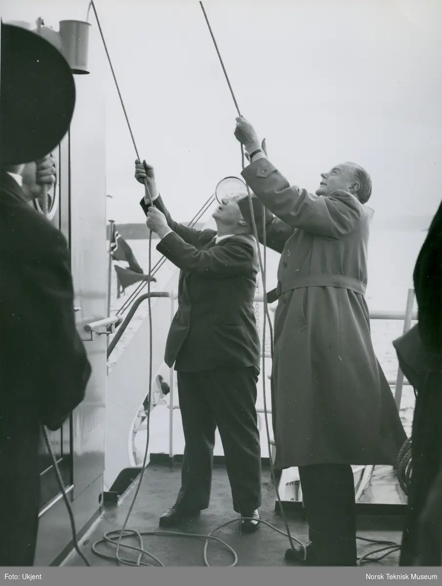 Ludvig Lorentzen (?) og direktør Aamundsen heiser flagg på lasteskipet M/S Breda, B/N 513 (Tangens B/N T3) under prøvetur i Oslofjorden. Skipet ble levert av Akers Mek. Verksted og Tangen Verft til Fred. Olsen & Co i 1957.