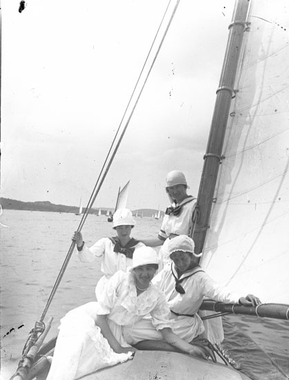 Enl. text i blå bok: "Damer vid mast på segelbåt"