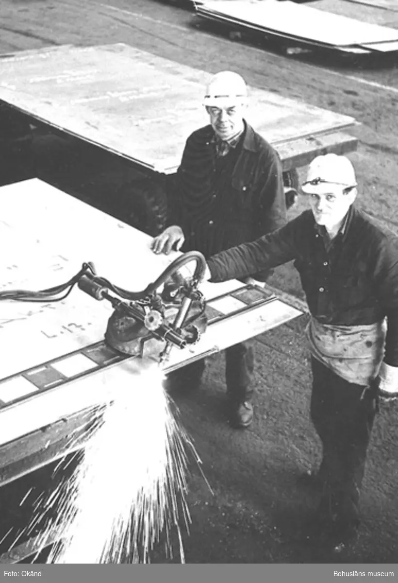 Två varvsarbetare skär i metall med skärbrännare
