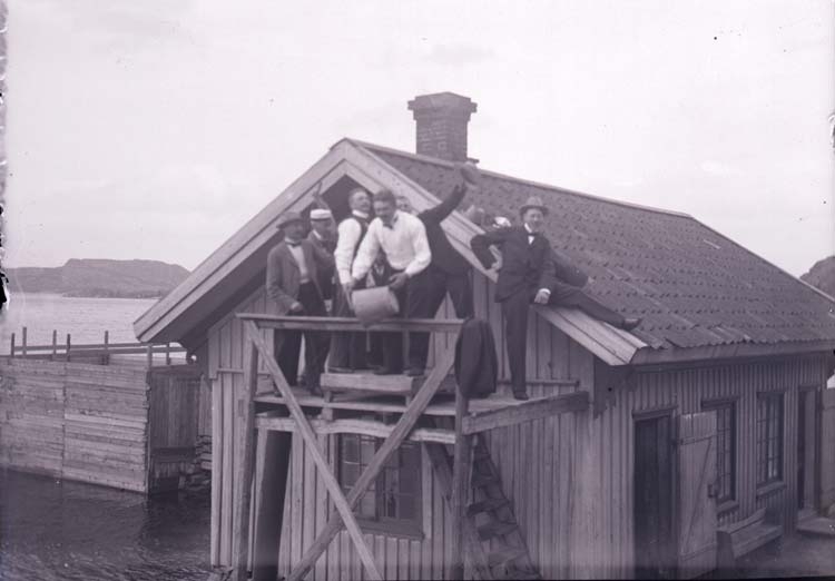 Enligt text som medföljde bilden: "Henån, Engelbert, Valter, Primus m.fl. vid pumpen på Badhuset. 28/7 1901."