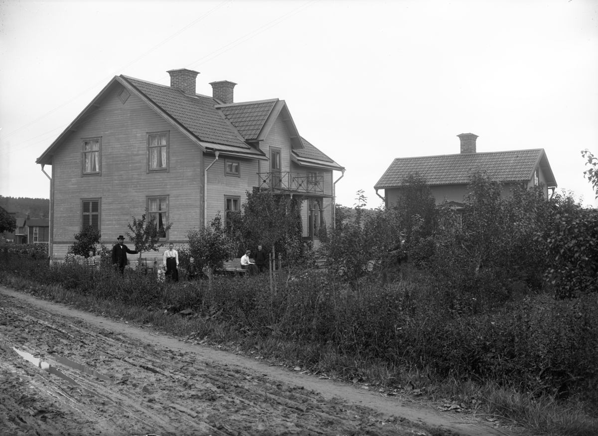 Familj framför bostadshus, oidentifierad