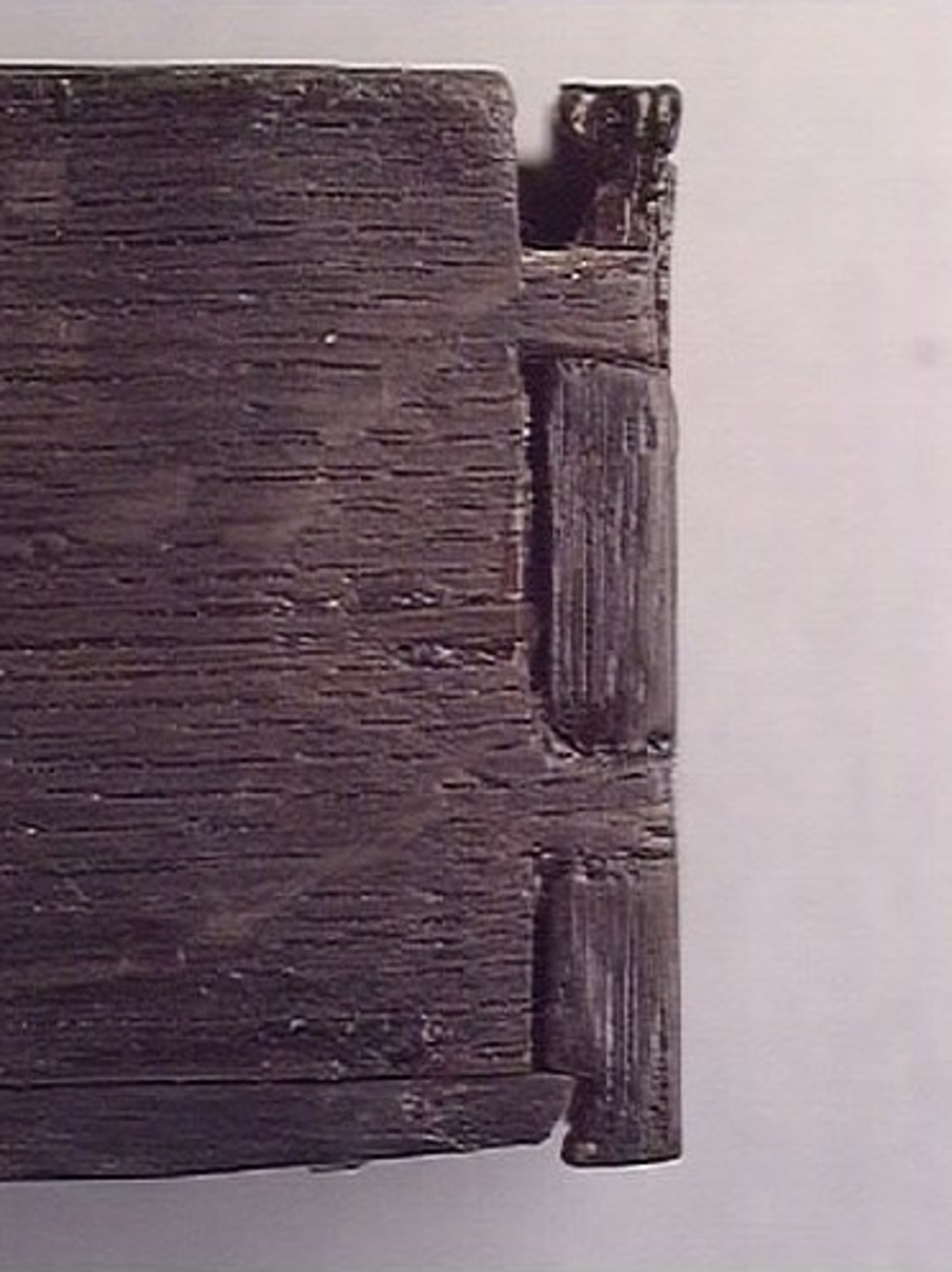 Ett litet träskrin med skjutlock.
Skrinets gavlar och långsidor är sinkade. Bottnen sitter infälld i gavlarna och är fästad med trästift vid långsidorna. Skrinet är försett med tre, löstagbara mellanväggar. På insidan av skrinet finns spår för mellanväggarna och för locket. Lockets ena ände är profilerad och har en liten halvcirkelformad urholkning som fungerar som tumgrepp. Den profilerade änden skjuter ut en bit utanför skrinet, då locket är stängt.
Två av skrinets mellanväggar samt en av långsidorna är rekonstruerade. Längs med skrinets ena långsidan löper en spricka. Skrinet är i gott skick.