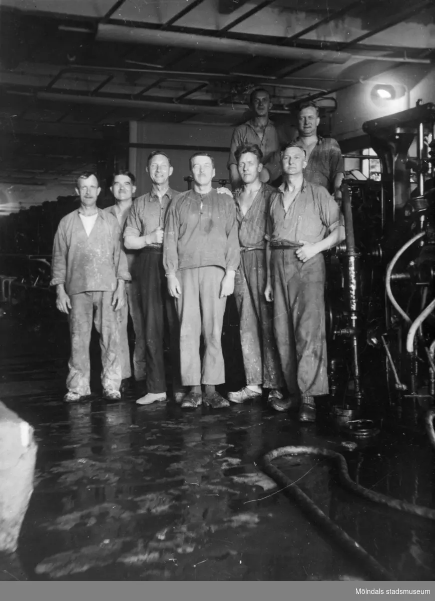 Papyrusarbetare uppställda framför maskinerna inuti fabriken ca 1930. Mannen längst till höger i främsta raden är Artur Svensson, född 1892.