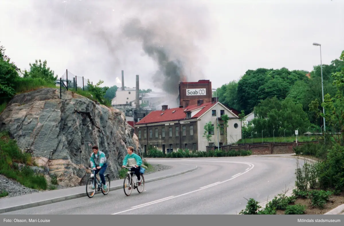 Soab-branden i Stora Götafors den 4 juni 1986. Två personer som cyklar utanför Papyrus mur.