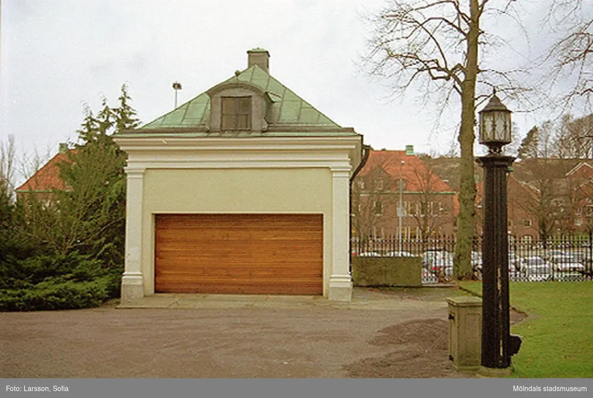 Garagebyggnad tillhörande Villa Papyrus. I bakgrunden syns parkerade bilar samt den röda tegelbyggnaden Kvarnbyskolan.