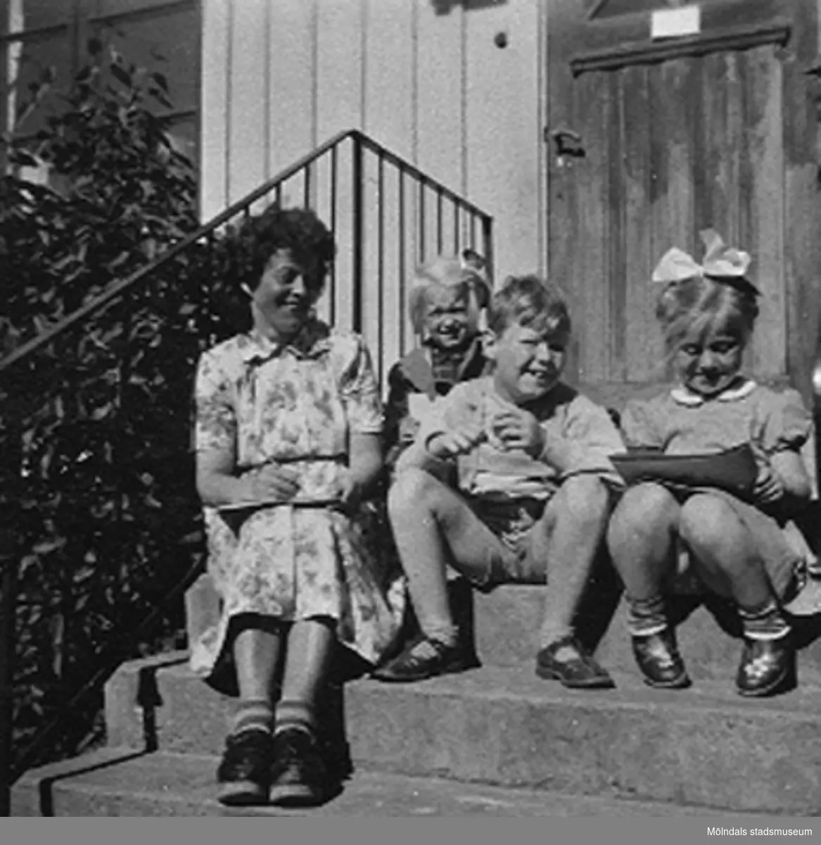 Tre barn och bitr. föreståndare Margit Emilsson (gift Wannerberg -52) sittande på trappan till Krokslätts daghem, Dalhemsgatan 7 i Krokslätt, 1948 - 1951.