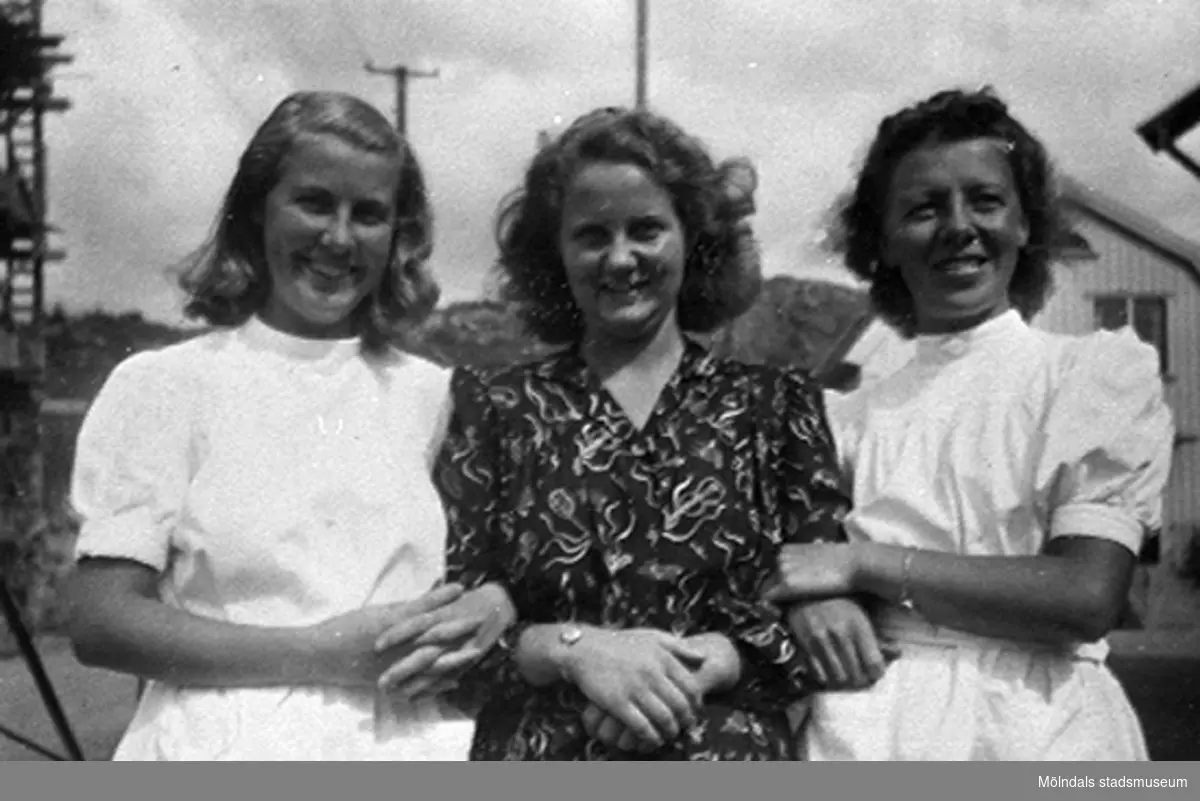 Två okända kvinnor står på var sin sida om praktikanten Margit Emilsson (gift Wannerberg -52)  vid Krokslätts daghem. 
Under Margits praktik som biträde 1945-10-01 - 1946-08-01.