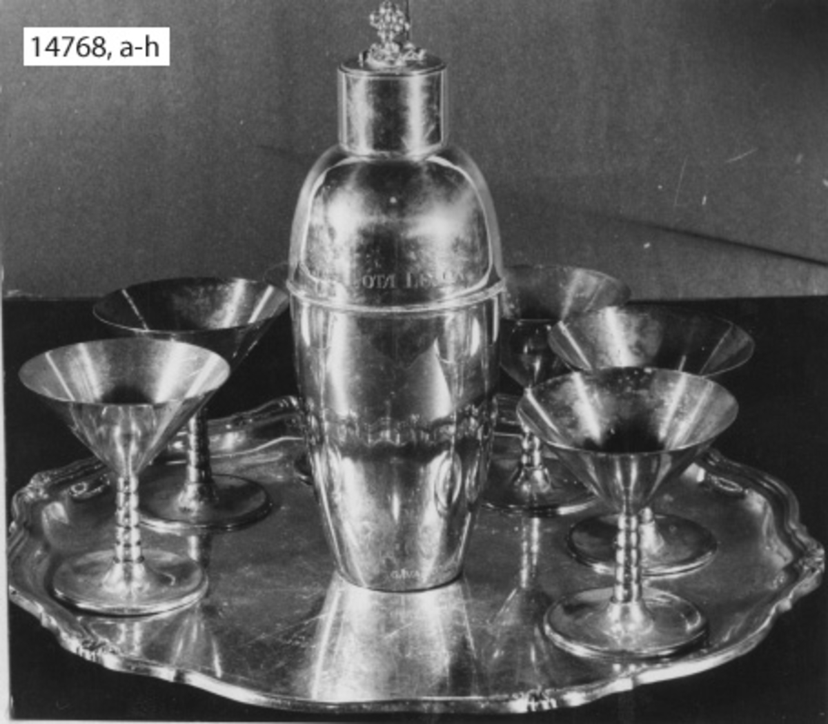 Servis, cocktail-, av silver. Tumlare. Ingravering: H.M. KRYSSAREN GÖTA LEJON. (Skänkt till kajutan).