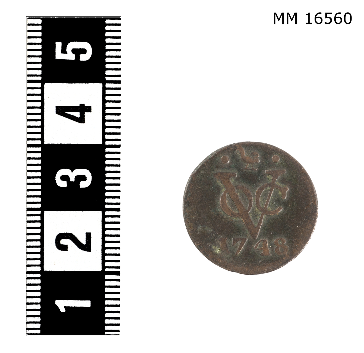 Mynt, 1 dmt, ostindiska komp. Ena sidan: upphöjd relief: "Voc 1748". Andra sidan: upphöjd relief: krönt vapensköld med två lejon. Innanför myntets kant har funnits någon form av upphöjd ornamentering.