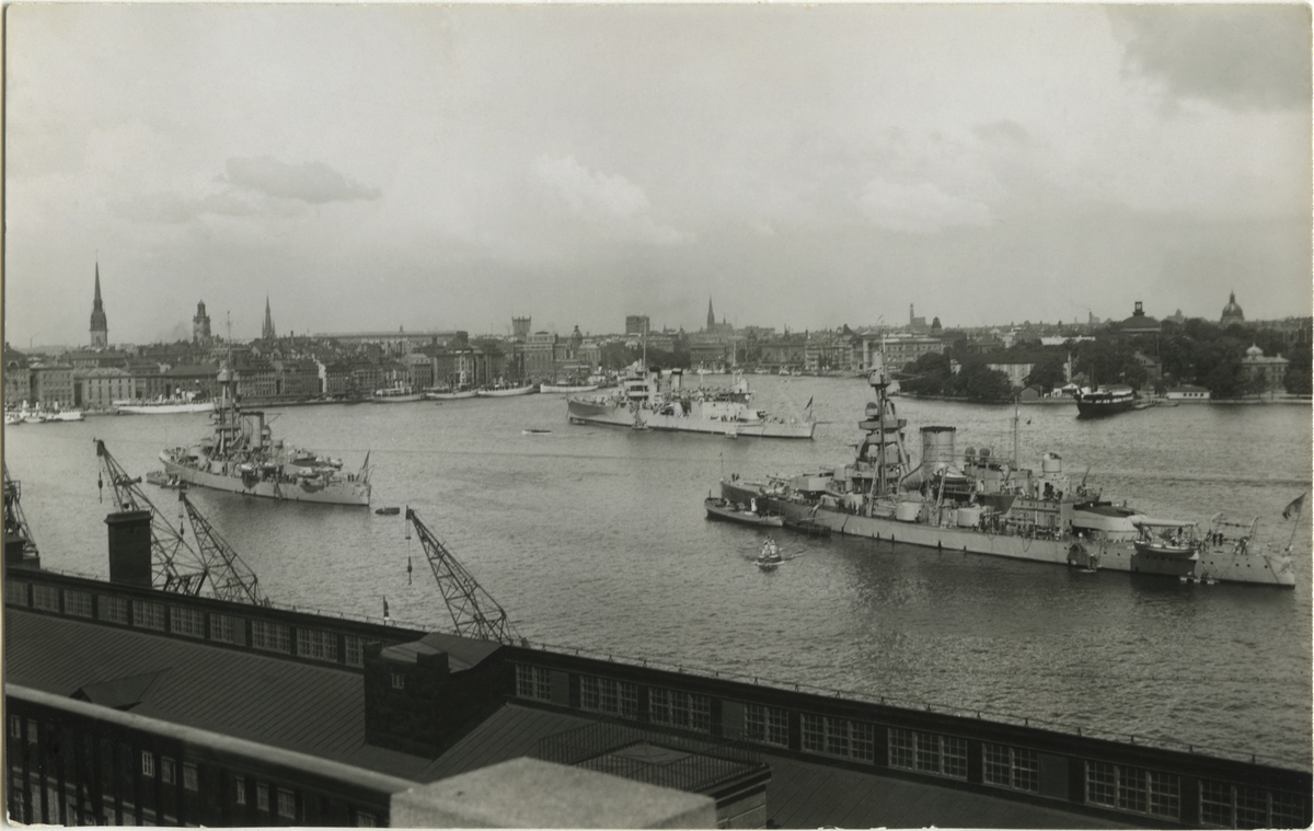 Eskaderbild tagen i maj 1934 då den amerikanska tunga kryssaren NEW ORLEANS (b. 1933, i bakgrunden i mitten) på sin "shakedown cruise" i nordeuropeiska hamnar besökte Stockholm. I förgrunden t h pansarskeppet GUSTAF V, t v SVERIGE. Förtöjt vid Skeppsholmen i bakgrunden t h logementsfartyget (ex ångfregatten) VANADIS (b. 1862).