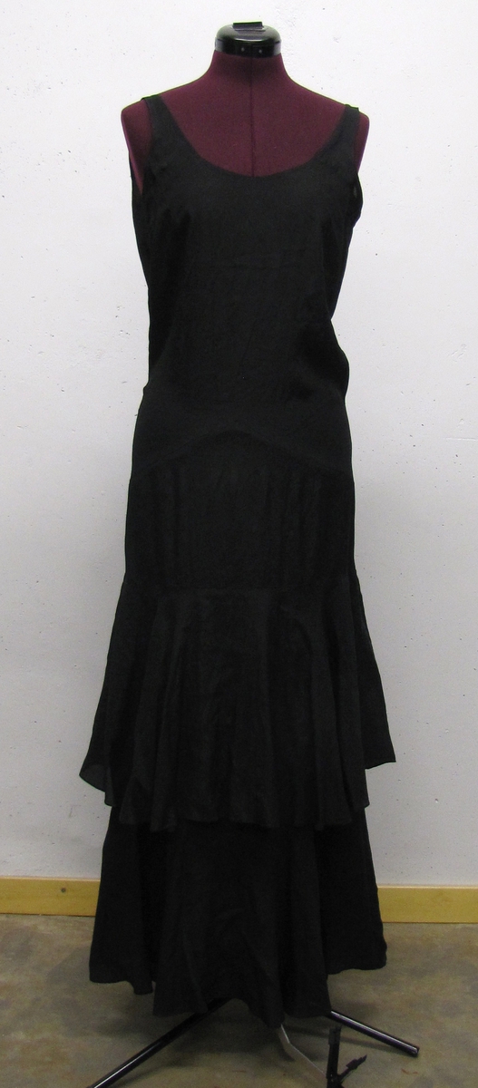 Ärmlös, svart smokingklänning, v-ringad. Kjol i två lager, stor vidd i kjolen. 
 
Jämför VM 12 058

Klänningen är från 1920-talet.