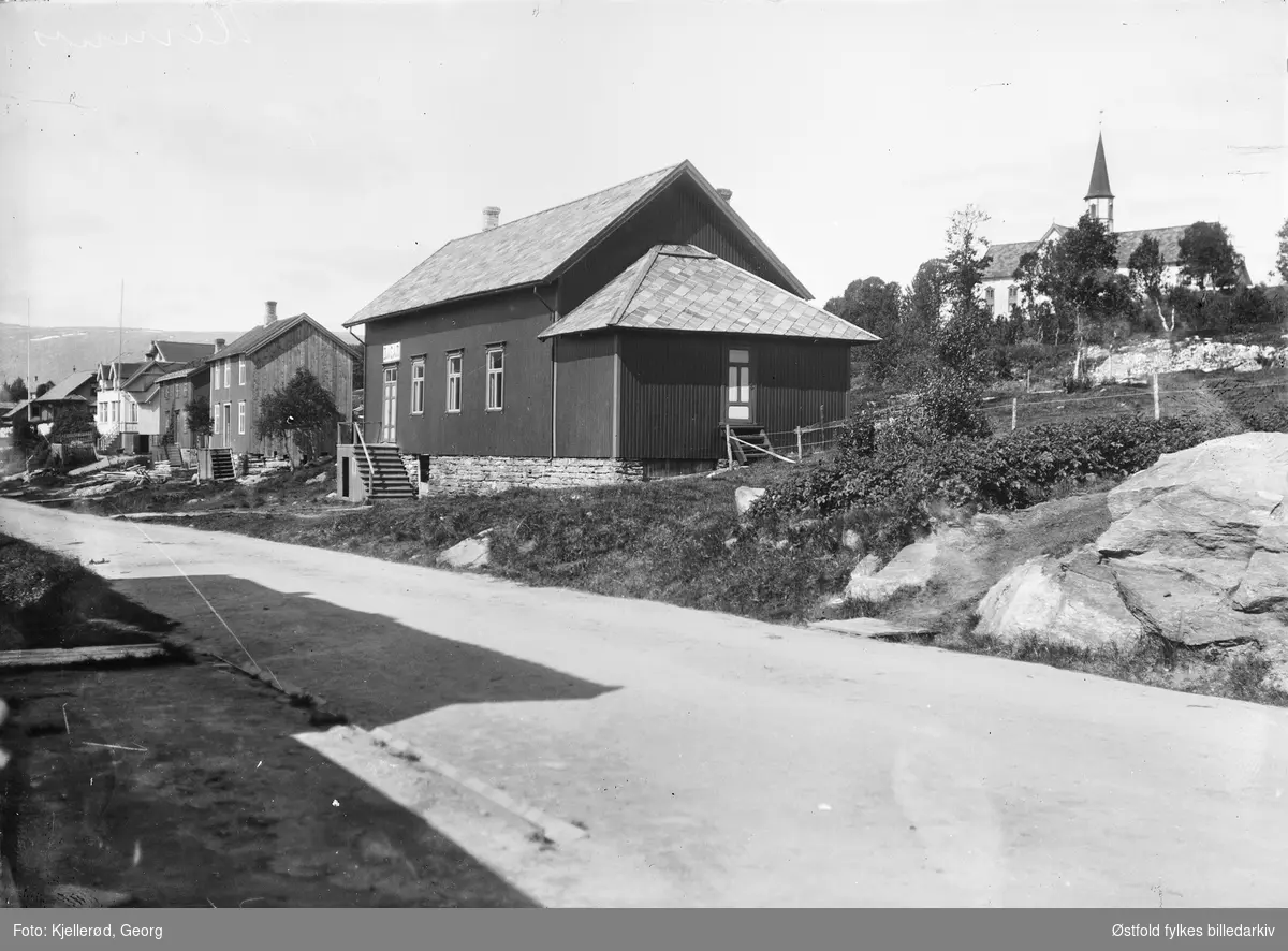 Gateparti fra Hemnesberget i Nordland, på huset nærmest  skilt med BASAR. Hemnes kirke i bakgrunnen.